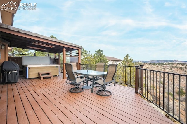 wooden deck featuring outdoor dining space, area for grilling, and a hot tub