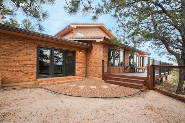 exterior space with french doors, brick siding, and a wooden deck