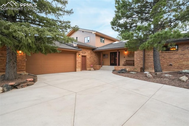 view of front of home featuring a porch, concrete driveway, and brick siding