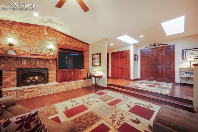 living area with vaulted ceiling with skylight, recessed lighting, a fireplace, wood finished floors, and baseboards