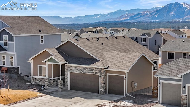 view of front of home featuring a residential view, a mountain view, an attached garage, and stone siding