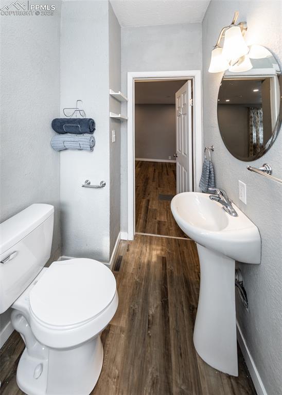 bathroom with wood finished floors, toilet, and baseboards