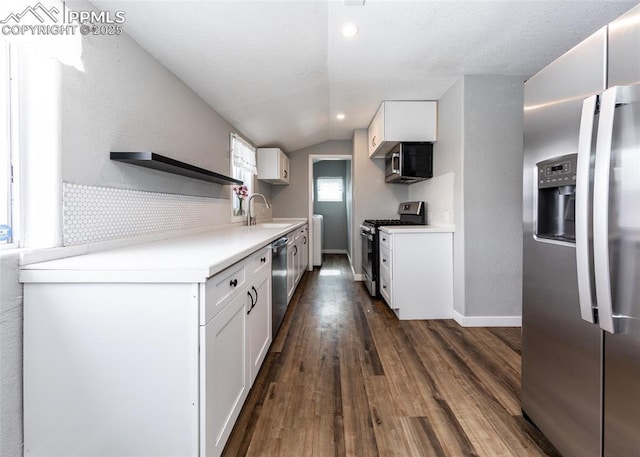 kitchen with a sink, white cabinets, light countertops, appliances with stainless steel finishes, and dark wood-style floors