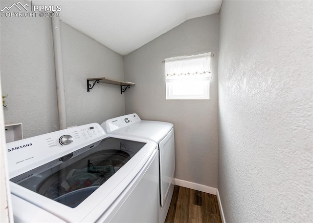 clothes washing area featuring a textured wall, washing machine and dryer, laundry area, wood finished floors, and baseboards