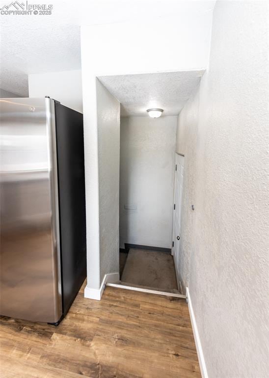 stairway featuring a textured ceiling, a textured wall, and wood finished floors