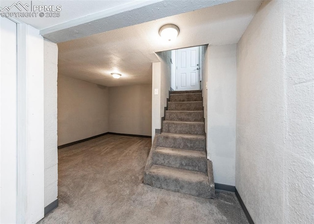 staircase with carpet flooring, a textured wall, a textured ceiling, and baseboards