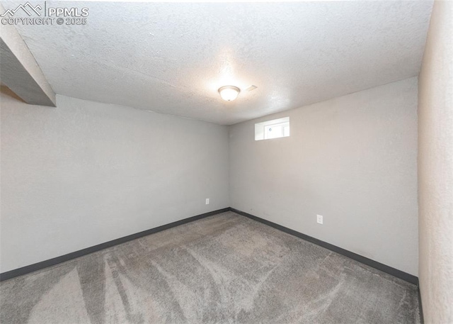 carpeted empty room with baseboards and a textured ceiling