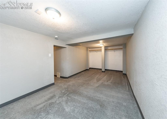 carpeted spare room featuring baseboards, a textured ceiling, and a textured wall