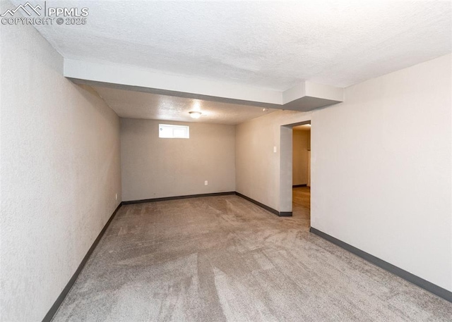 below grade area featuring a textured ceiling, carpet, and baseboards