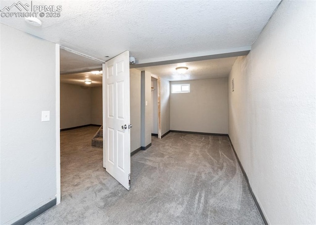 below grade area with baseboards, a textured ceiling, and light colored carpet