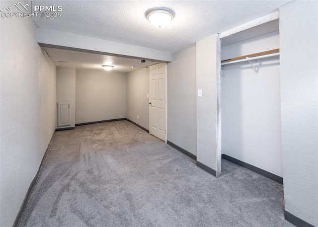 unfurnished bedroom with light carpet, a closet, baseboards, and a textured ceiling