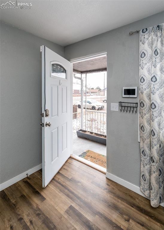 foyer entrance featuring dark wood finished floors, a textured ceiling, and baseboards