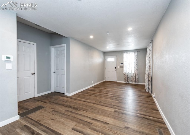 foyer entrance with visible vents, baseboards, and dark wood finished floors