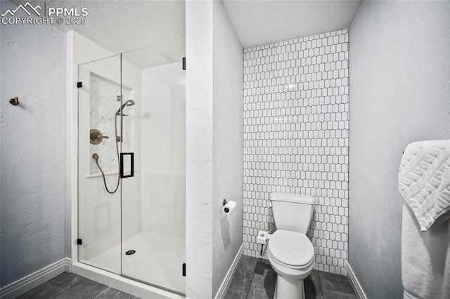 bathroom with toilet, a stall shower, baseboards, and a textured wall