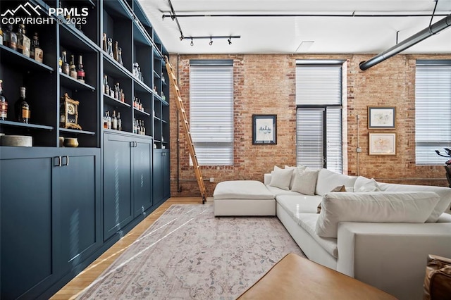 interior space with rail lighting, light wood finished floors, and brick wall