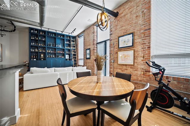 dining area featuring wood-type flooring, a dry bar, and brick wall