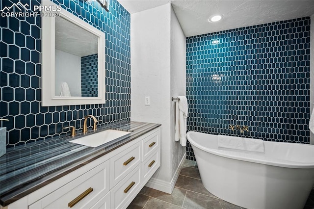 bathroom featuring backsplash, a textured ceiling, vanity, a freestanding tub, and tile patterned floors