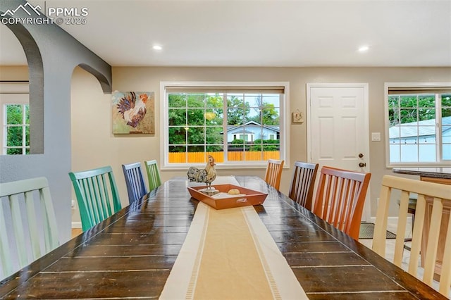 dining area featuring a wealth of natural light, arched walkways, and recessed lighting