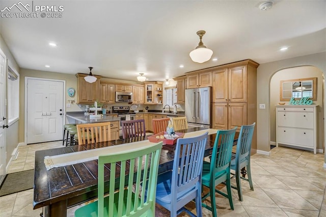 dining room with light tile patterned flooring, baseboards, arched walkways, and recessed lighting