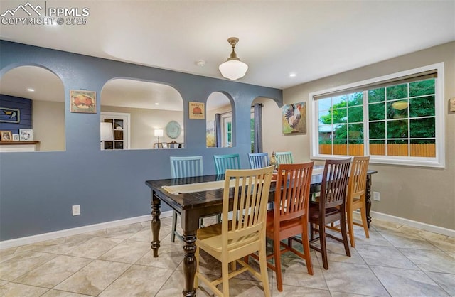 dining room featuring tile patterned flooring, baseboards, arched walkways, and recessed lighting