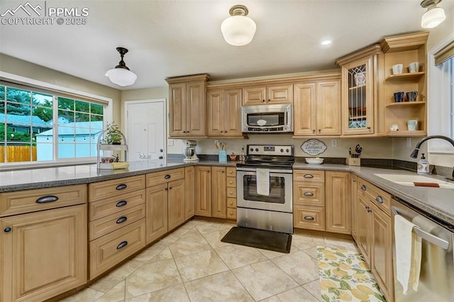 kitchen featuring stainless steel appliances, a sink, dark stone counters, glass insert cabinets, and pendant lighting