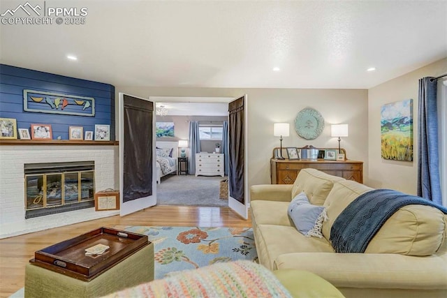 living area with a brick fireplace, baseboards, wood finished floors, and recessed lighting