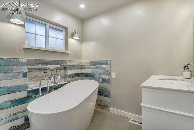 full bathroom featuring a freestanding tub, vanity, baseboards, visible vents, and tile patterned floors