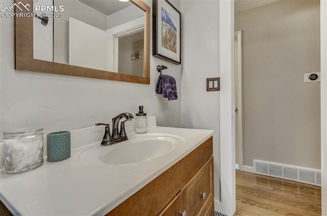 bathroom featuring baseboards, visible vents, wood finished floors, and vanity