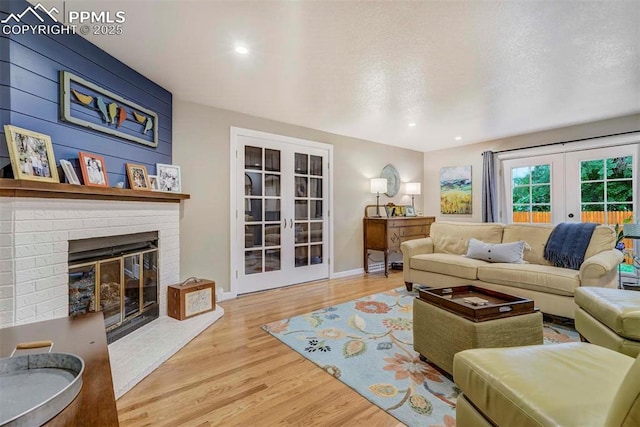 living area featuring recessed lighting, wood finished floors, baseboards, french doors, and a brick fireplace