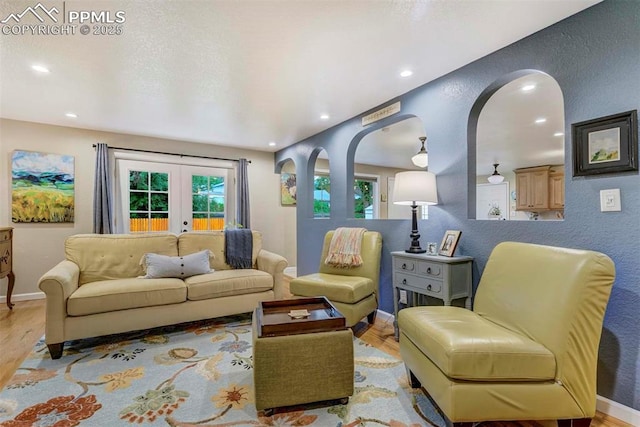 living area with french doors, a textured wall, and wood finished floors