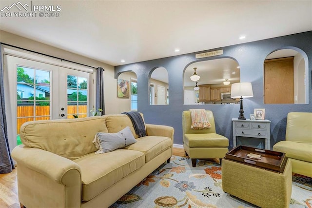 living area featuring light wood-type flooring, french doors, a textured wall, and recessed lighting