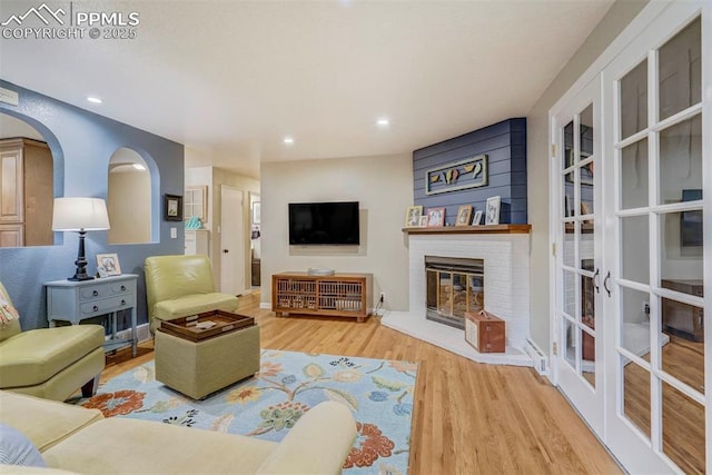 living area with recessed lighting, a brick fireplace, arched walkways, and wood finished floors