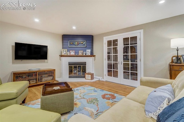 living area featuring recessed lighting, a brick fireplace, french doors, and wood finished floors