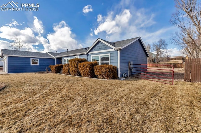 view of side of home featuring fence and a lawn