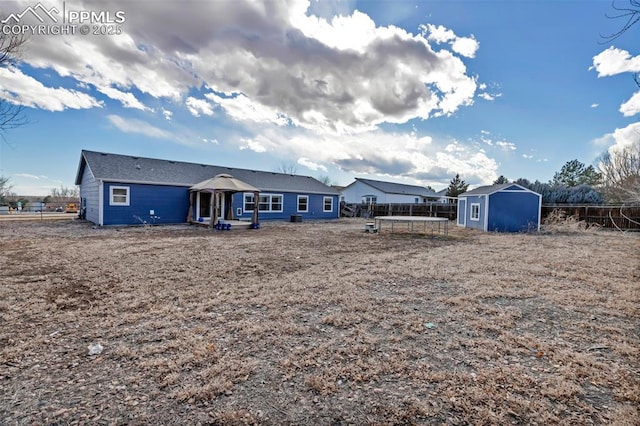 back of house with a shed, fence, and an outbuilding