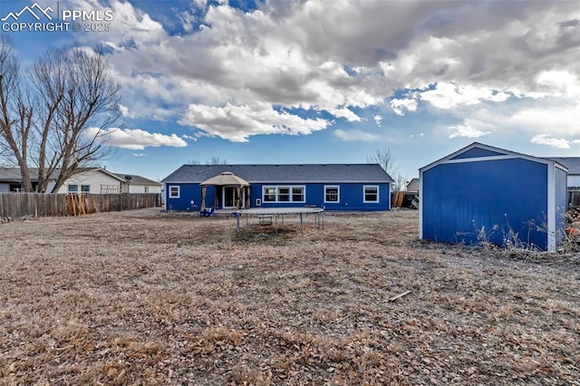 rear view of property with a trampoline and fence