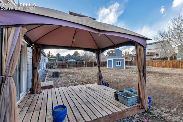 wooden terrace featuring a storage shed, a fenced backyard, an outdoor structure, and a gazebo