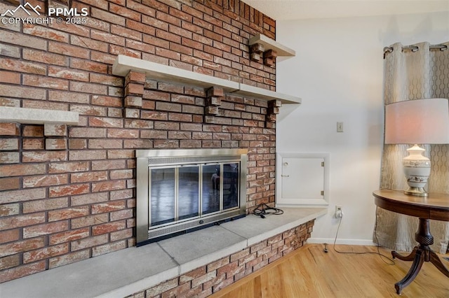 interior details featuring a fireplace, baseboards, and wood finished floors