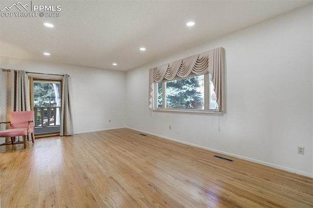 empty room featuring light wood-style floors, recessed lighting, visible vents, and baseboards