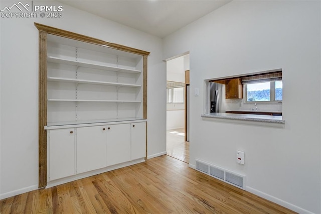 spare room featuring light wood finished floors, baseboards, and visible vents