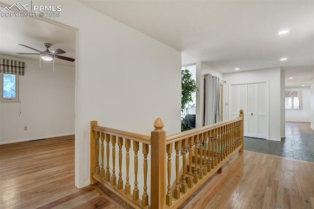 hallway featuring baseboards, an upstairs landing, and wood finished floors