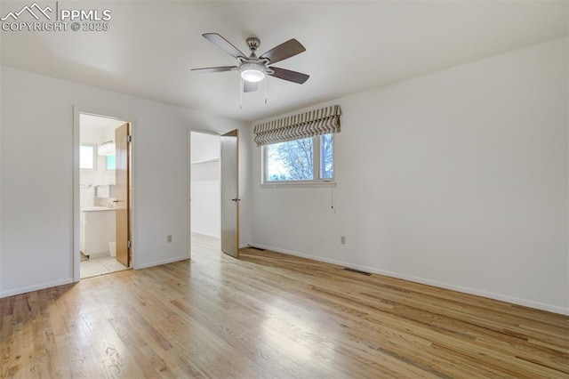 unfurnished bedroom with light wood-type flooring, ensuite bath, a spacious closet, and baseboards