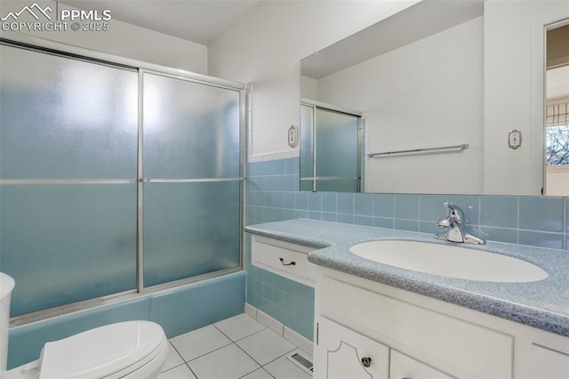 bathroom featuring toilet, vanity, combined bath / shower with glass door, and tile patterned floors