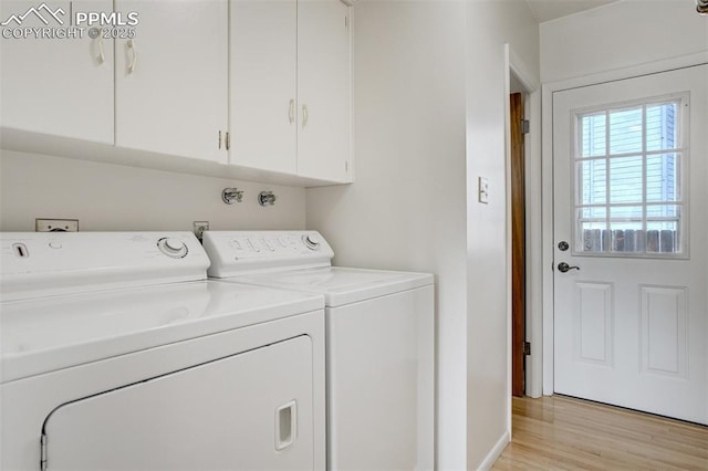 clothes washing area featuring light wood-style floors, cabinet space, and washing machine and clothes dryer