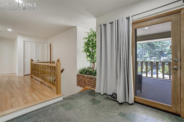 hallway featuring stone tile flooring and an upstairs landing