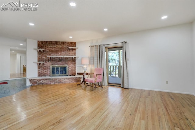 living area with recessed lighting, a brick fireplace, baseboards, and wood finished floors