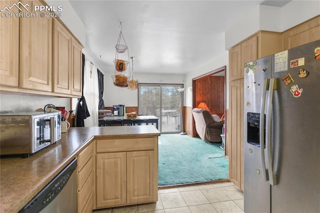 kitchen with light brown cabinetry, appliances with stainless steel finishes, and a peninsula