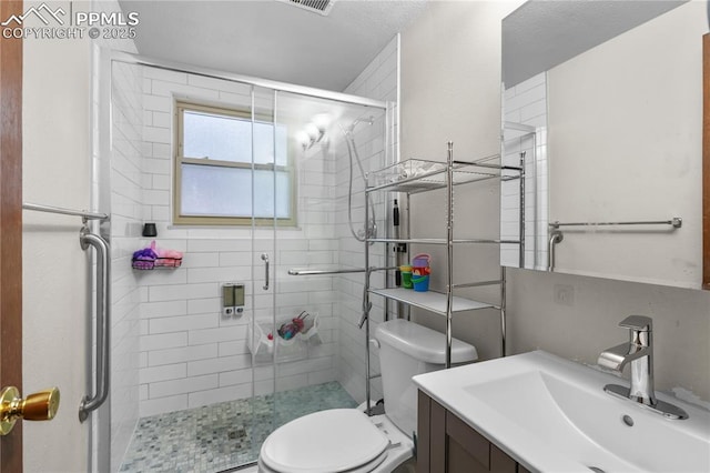 bathroom with a shower stall, toilet, and vanity