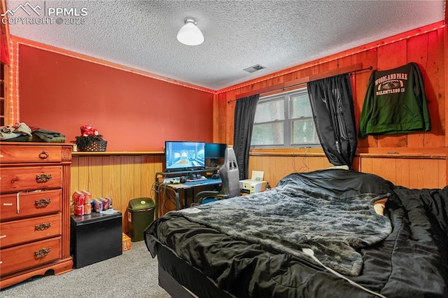 bedroom featuring carpet floors, visible vents, wood walls, and a textured ceiling