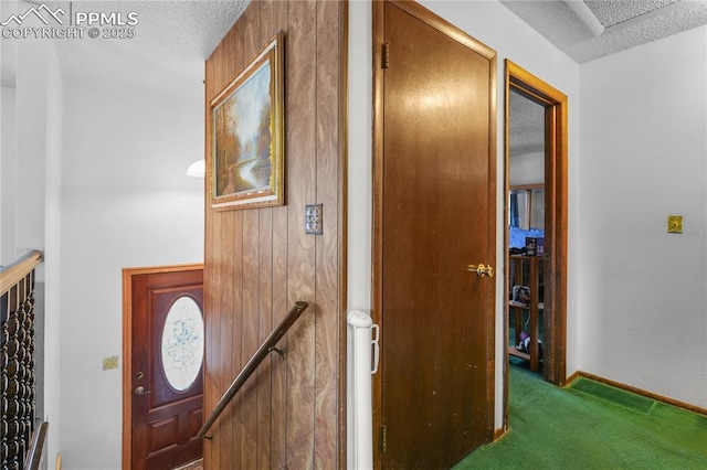 corridor featuring a textured ceiling, carpet flooring, an upstairs landing, and baseboards